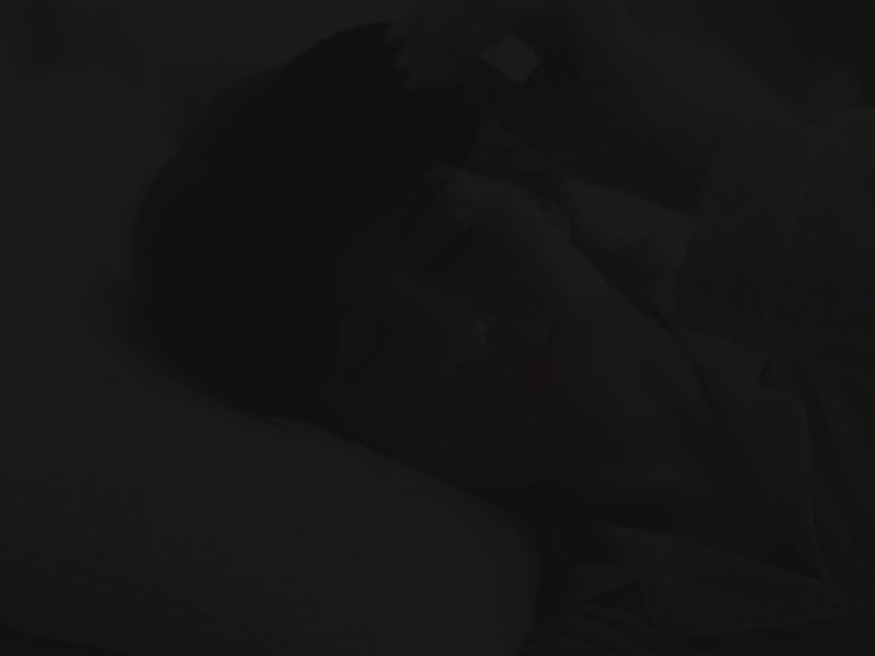 Putting on the black 3D Contoured Sleep Mask in bed