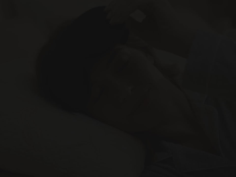 Putting on the black 3D Contoured Sleep Mask in bed